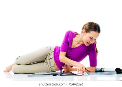 Young woman lying on the floor reading a magazine on white background studio - Powered by Shutterstock