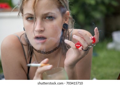 Young Woman Lying On Garden Grass Having Beer And Smoking Cigarette Looking At Camera.  