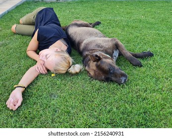 young woman lying on grass with her dog. relaxing lady and animal. tired girl taking a rest in the garden.