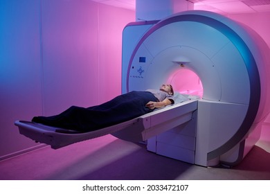 Young Woman Lying On Long Table Of Medical Equipment Before Undergoing Mri Scan Examination