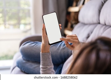 Young Woman Lying On Sofa At Living Room And Using Cell Phone At Home