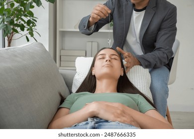 Young woman lying on sofa during hypnosis session at psychologist office - Powered by Shutterstock