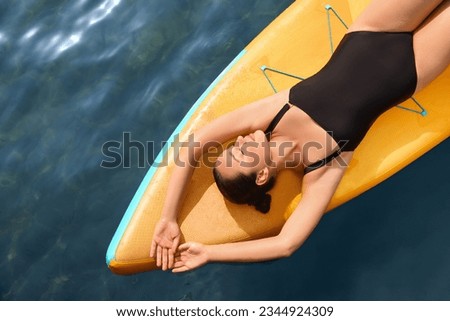 Young woman lying on SUP board in sea, top view. Space for text