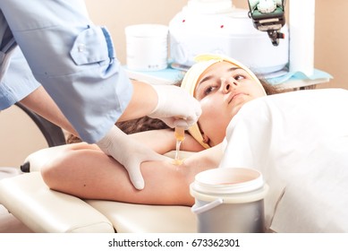 A young woman is lying on a table and she is undergoing epilation by sugar - Shutterstock ID 673362301