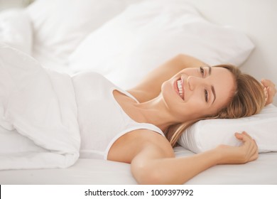 Young Woman Lying On White Pillow In Bed