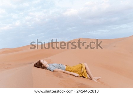 Young woman lying in sand dune in sahara desert- merzouga- morocco