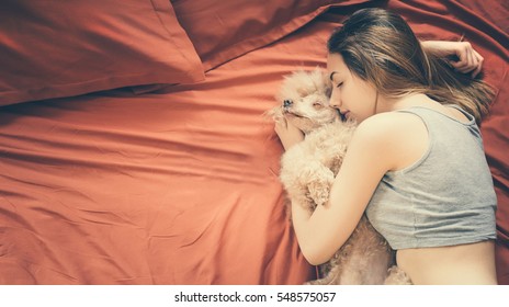 Young Woman Is Lying And Sleeping With Poodle Dog In Bed.