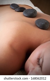 Young Woman Lying In A Spa Ready To Get A Massage With Rocks On Her Back