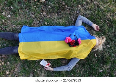 Young Woman Lying Under The Ukrainian Flag On The Ground In Nature. Symbol Of Empathy With Victimes Of War Conflict 2022. Europe. Ukraine And Russia. Dead Girl. Flower Wreath.