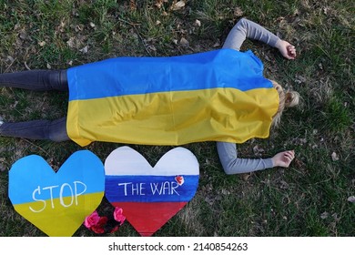 Young Woman Lying Under The Ukrainian Flag On The Ground In Nature. Symbol Of Empathy With Victimes Of War Conflict 2022. Europe. Ukraine And Russia. Dead Girl. Flower Wreath.