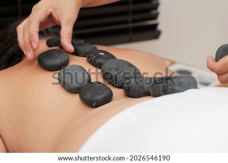 Young woman lying while receiving a spa treatment with hot stones on her back