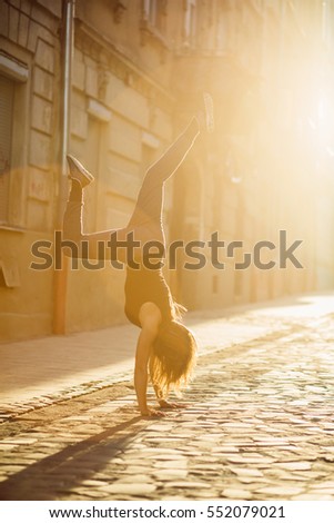 Young woman make handstand  in the summer sunny morning. Handstand exercise. Conception of youth and energy. Vertical.