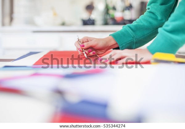 Young woman make scrapbook of the papers on the\
table using antique tools for cutting paper. Hand made photo\
album.Shallow depth of\
field