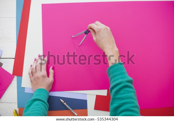 Young woman make scrapbook of the papers on the\
table using antique tools for cutting paper. Hand made photo\
album.Shallow depth of\
field
