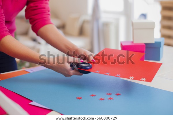 Young woman make scrapbook of the papers on the\
table using tools for cutting paper. Hand made photo album.Shallow\
depth of field