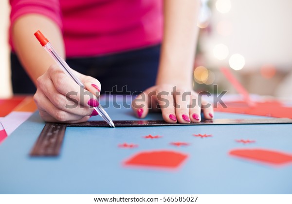 Young woman make scrapbook of the papers on the\
table using tools for cutting paper. Hand made photo album.Shallow\
depth of field