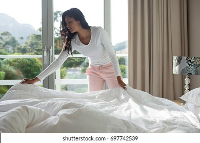 Young Woman Making Bed At Home