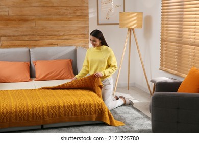 Young Woman Making Bed In Room. Modern Interior With Sleeper Sofa