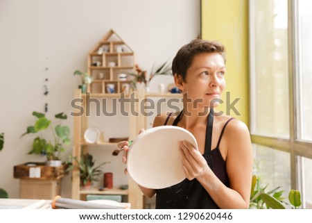 Similar – Image, Stock Photo Young female sitting by table and making clay or ceramic mug