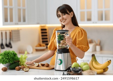 Young woman making delicious smoothie with blender at white marble table in kitchen - Powered by Shutterstock