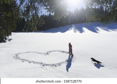 Young Woman Making Heart Shape In Snow