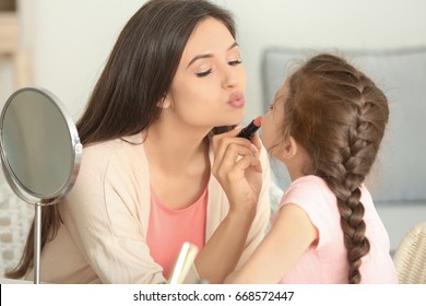 Young woman making up her daughter at home