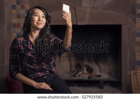 Young woman making a photo of a fireplace with telephone