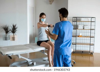 Young Woman Making Physiotherapy Session With Doctor Or Physiotherapist In A Big Health Center Or Clinic, Strength Shoulder Rehabilitation Exercises. Physical Therapy During Covid-19 Outbreak.