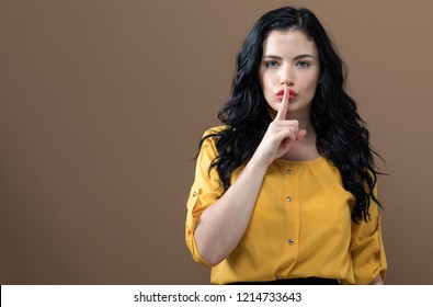 Young woman making a quiet gesture on a solid background