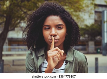 A young woman making silence gesture