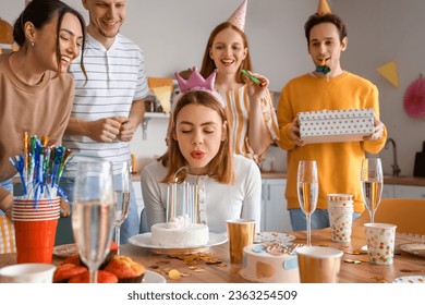 Young woman making wish at birthday party with her friends - Powered by Shutterstock