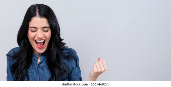 Young Woman Making A Yay Gesture On A Gray Background