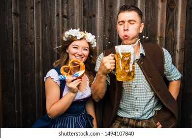 Young woman and man with beer mug and pretzel on a wood background .Oktoberfest concept