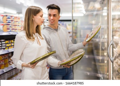 Young Woman And Man Buying Frozen Pizza At Grocery Store