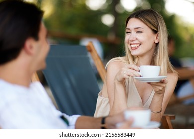 Young woman and a man enjoy coffee and chat in a summer cafe - Shutterstock ID 2156583449