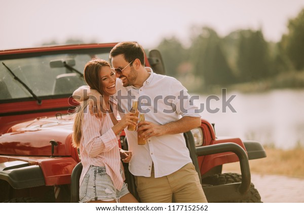 Young woman and man having fun outdoor near car at\
summer day