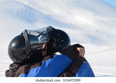 A Young Woman And A Man In Helmets Kiss After A Quad Bike Ride In Svalbard. The Couple Are Happy To Have Conquered The Winter Track.