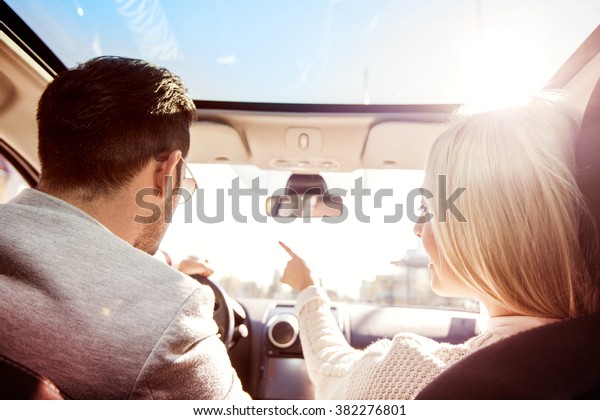 A young woman and a young\
man are laughing in the car,enjoying in the road trip.The man is\
driving.
