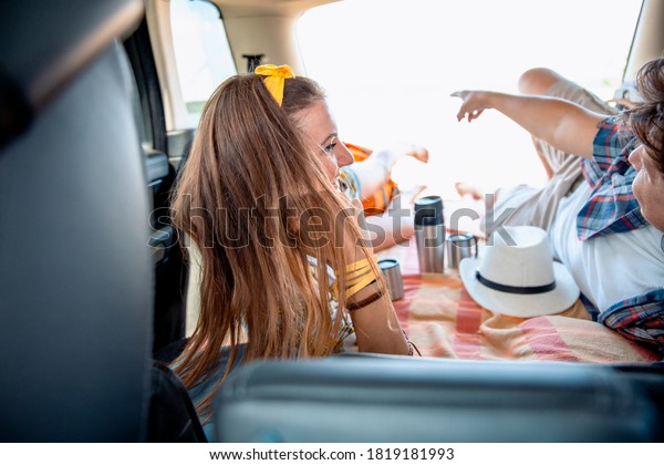 Young Woman and Man\
laying together in the Car Trunk enjoying in their picnic,\
travelling on sunny day
