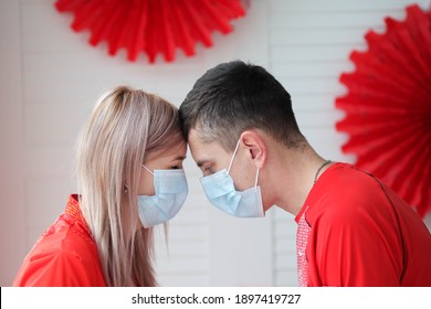 A young woman and a man in medical masks bowed their heads. Valentine's day amid the covid-19 pandemic.
