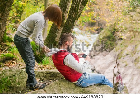 Young woman and man are photographed on the phone at the edge of the mountain