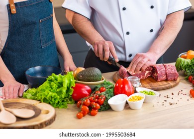 Young Woman And Man Prepare Food And Host A Cooking Show. The Bloggers Stream From Modern Kitchen. Healthy Food Preparation.