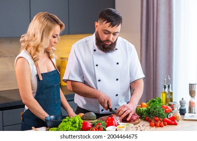 Young Woman And Man Prepare Food And Host A Cooking Show. The Bloggers Stream From Modern Kitchen. Healthy Food Preparation.