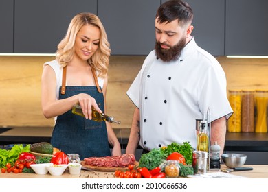 Young Woman And Man Prepare Food And Host A Cooking Show. The Bloggers Stream From Modern Kitchen. Healthy Food Preparation.