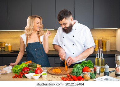 Young Woman And Man Prepare Food And Host A Cooking Show. The Bloggers Stream From Modern Kitchen. Healthy Food Preparation.