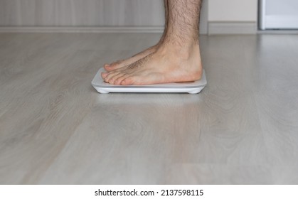 Young Woman Or Man Is Sitting Or Steping On Modern Scale For Weight Measurements. Body Fat Scale Accurate. Body Composition Monitor, White Color On Grey Floor. Weight Control. Diet And Fitness Concept