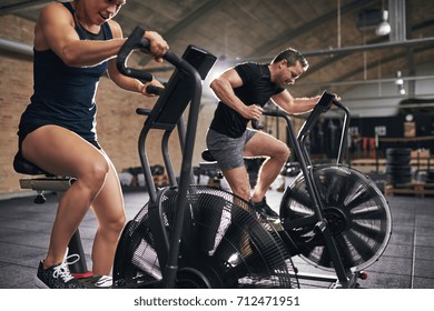 Une jeune femme et un homme en vêtements de sport se sont concentrés sur le vélo en salle de sport. 