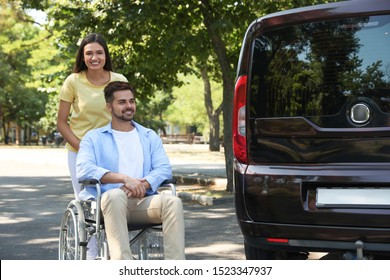 Young Woman With Man In Wheelchair Near Van Outdoors