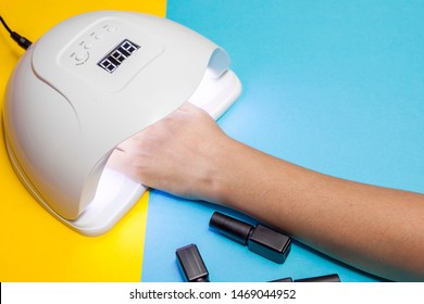 A Young Woman At Manicure Procedure. Woman Nail Polish Process. Female Using Shellac Uv Led Lamp.