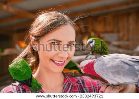 Young woman with many colourful parrot birds around, sitting on her shoulder